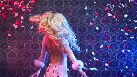 Young woman dancing with confetti , slow - motion