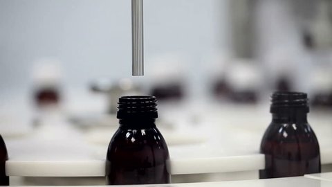 Adding Meds. Medicine Bottles Being Filled With Liquid on a Conveyor