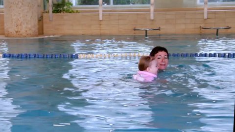 Cute two-year girl on first swimming lessons with her mom