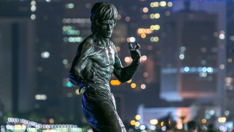 HONG KONG, CHINA - SEPTEMBER 15: Bruce Lee monument timelapse hyperlapse in the night at the Avenue of stars, modern skyscrapers at the background in Hong Kong. Bruce Lee was the most influential. 4K