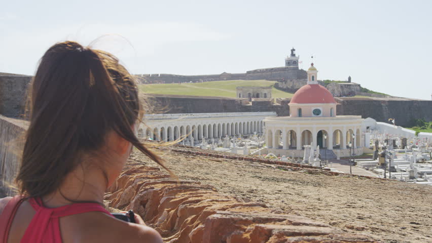 Puerto Rico tourist taking photo at Old San El Morro and Cemetery by Fort Castillo San Felipe Del Morro. Woman tourist on her Caribbean cruise visiting Santa Maria Magdalena de Pazzis Cemetery.