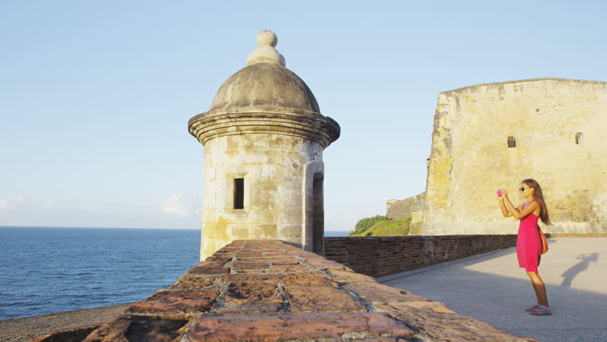Puerto Rico tourist taking photos with smart phone at Old San Juan Fort Castillo San Felipe Del Morro. Asian tourist on Caribbean cruise travel visiting a famous landmark during summer vacations.