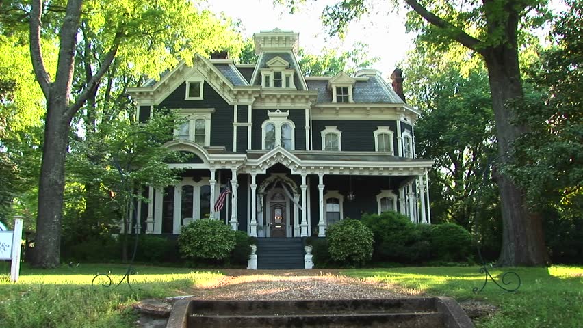 Old house surrounded by large leafy green trees