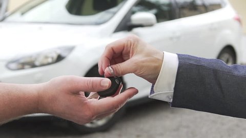 Car sale. A man selling a car to another man and handing over the key.