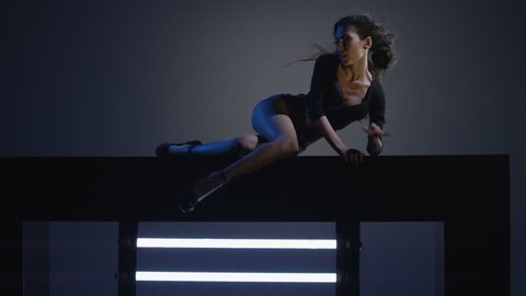 Sexy brunette dances on blue dark background. Beautiful girl dancing, laying on cube. Shot on RED EPIC DRAGON Cinema Camera in slow motion. 