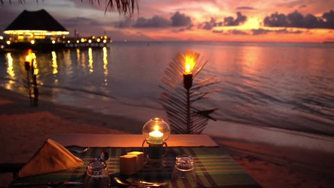 Served tables in the restaurant on the ocean in anticipation of visitors at sunset.