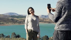 boyfriend taking photo of his girlfriend with beautiful landscape background 
