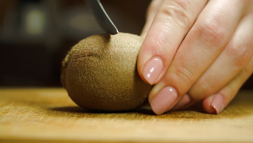 Woman Hands Cutting A Kiwi In Half