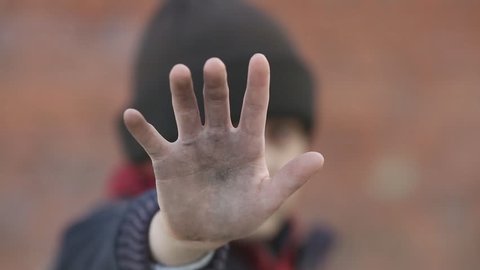 dramatic portrait of a little homeless boy, dirty hand, poverty, city, street