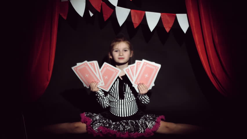 little girl shows focus with a large playing cards