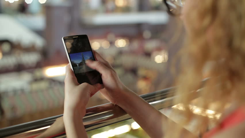 Woman uses a smartphone and write SMS in a shopping center