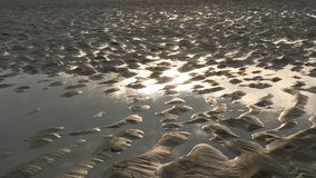 Tidal shapes of sand on the ocean coast and sun reflection 4K 3840X2160 UltraHD video - Wet sand and  water after tide ebb near ocean water 4K 2160p 30fps UHD footage