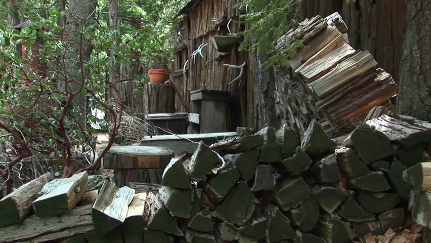 Medium shot of rural cabin with wood pile in the Sierra Nevada mountains.