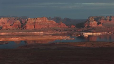 Wide shot of Lake Powell and luminous surrounding shoreline with sandstone cliffs.