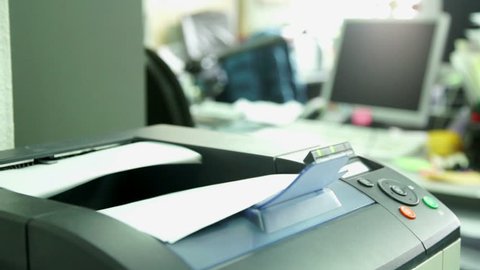 Printing document paper with laser printer. Office work and furnishings, stationery around in the background is seen the monitor