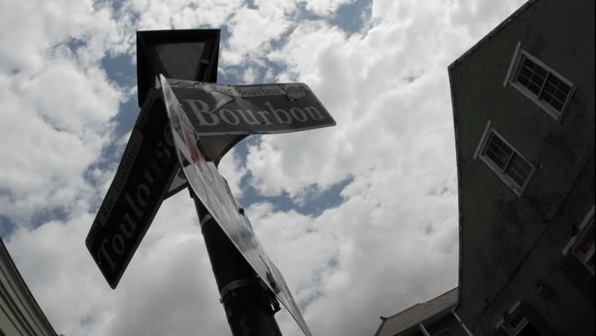 Low angle of Bourbon Street sign with time-lapse clouds in background
