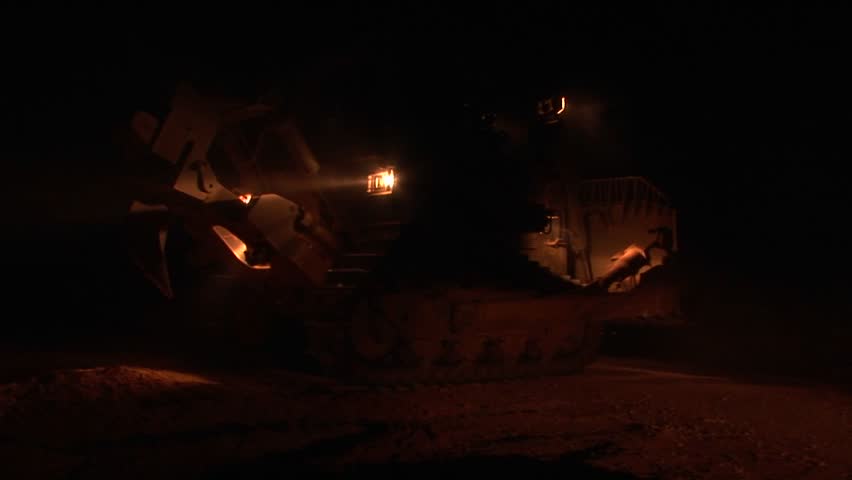 An Israeli armored bulldozer patrols the Israel-Gaza Strip border at night.