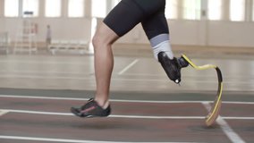 Tracking shot tilt-up of determined Paralympic athlete with prosthetic leg running on track in slow motion - Powered by Shutterstock - Get 15% off with code: PIKWIZARD15