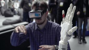 Cybernetic system today. Game industry and motion tracking in cyberspace. Man with innovative spectacles creates movement for mechanical plastic arm. Printing on the 3D printer. Sci Fi and prosthetics - Powered by Shutterstock - Get 15% off with code: PIKWIZARD15