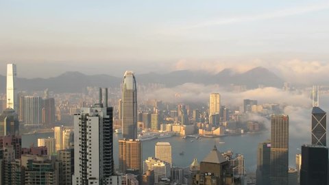 Time lapse Hong Kong skyline from famous Peak View at sunset. Fog comes into the city. Zoom in