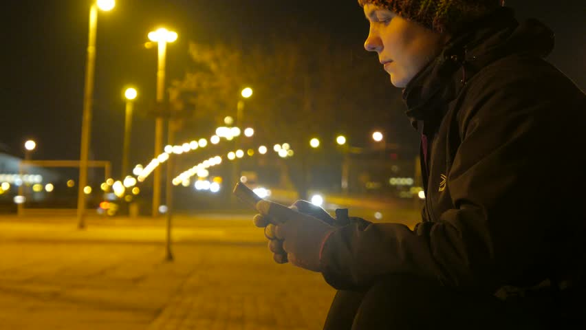 Girl wih a phone in her hands. Chatting on a night city background. 4K video.