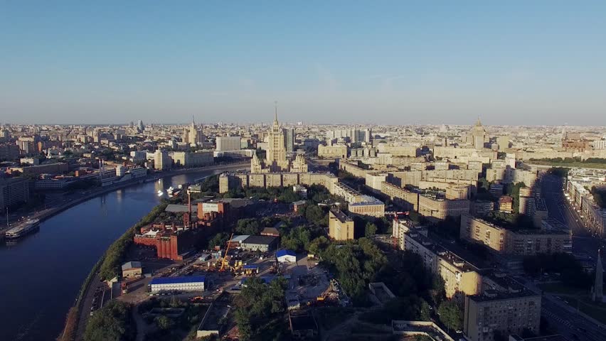 Quadrocopter fly over Moscow city in summer cloudless evening. Modern and old edifices. Building of Hotel. Moscow river