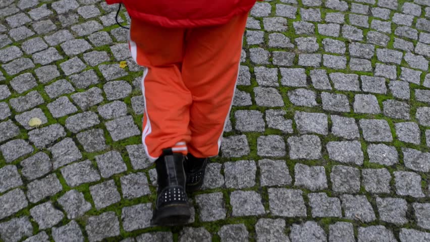 Little beautiful girl goes on the cobbled pavement in the old part of the European city.