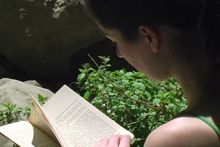 A woman reading a book in a beautiful setting.
