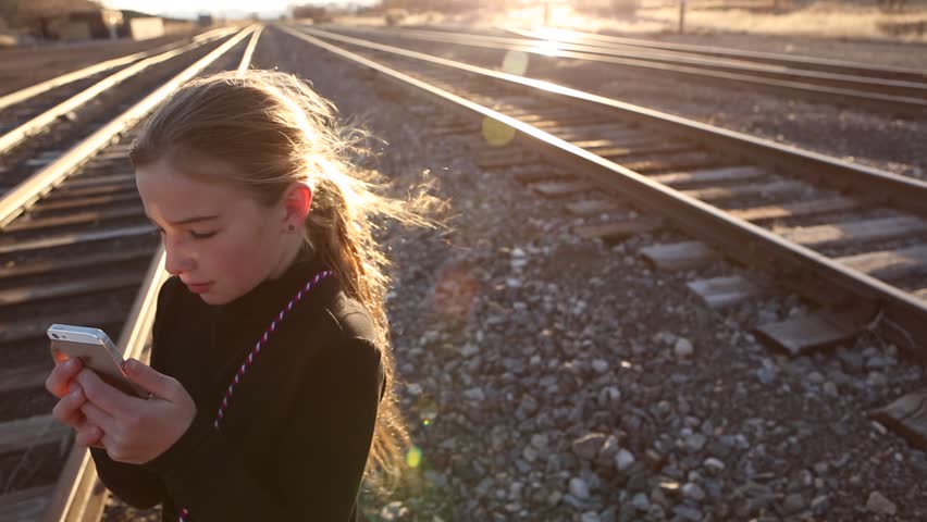  9 years old girl plays with a phone on a steel playground. Santa Fe, NM : March, 2016