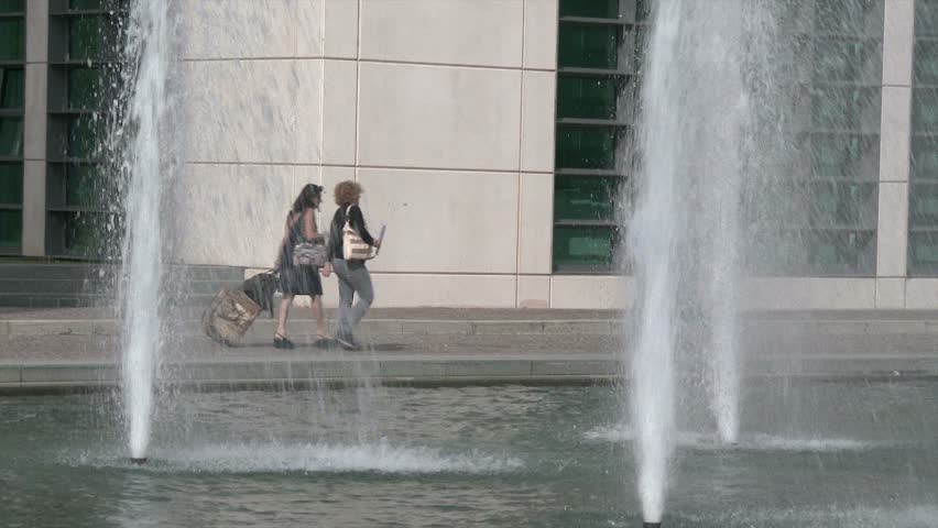 fountain jets and passersby with suitcase