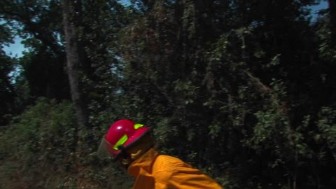 A firefighter walks quickly down a dirt road approaching a wildfire