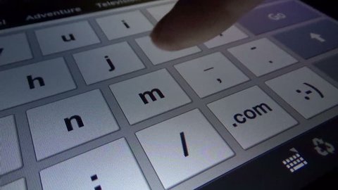 Fingers touching digital keyboard on touchscreen on iPad tablet device