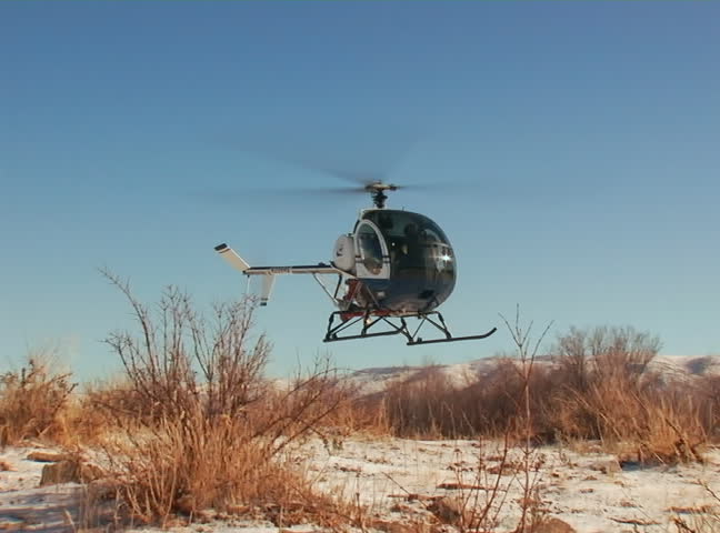 Schweizer 300C lands on mountain top. Winter.