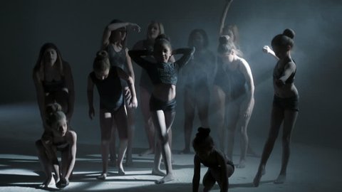 multi ethnic group female freestyle dancer dancing barefoot black leotard silhouette spot light powder flexible choreography