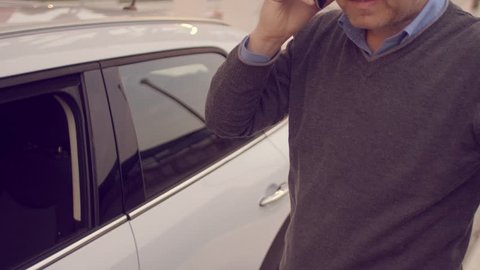 Man talking on the phone while charging its electric car

