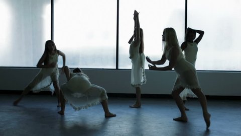 multi ethnic young female dancers dress barefoot indoor window silhouette dance studio creative musical expression choreography