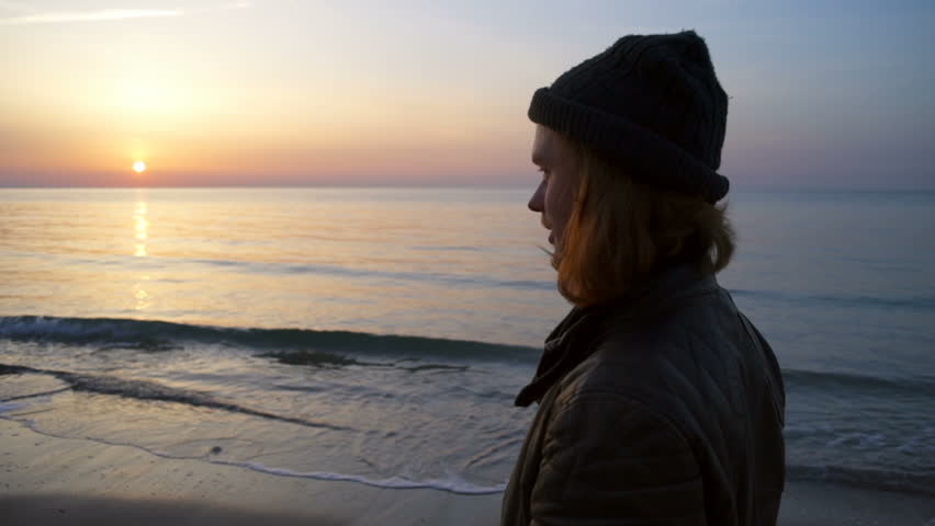 male skateboarder admiring the dawn by the sea slow motion 