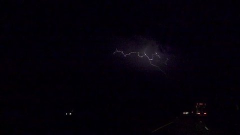 SLOW MOTION: Thunderstorm lightning bolt striking over the cars and trucks on a busy highway at night