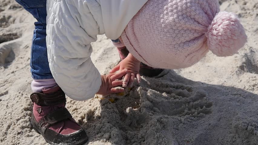 Little child girl playing with a sand on a sea shore