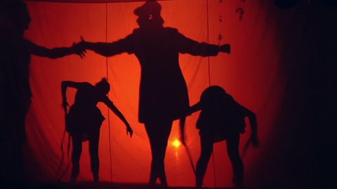 A man manipulates two women puppet over light red background. Bullying man with the two women