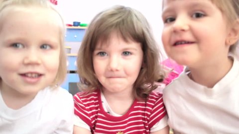 Little girls looking at the camera in a kindergarten.