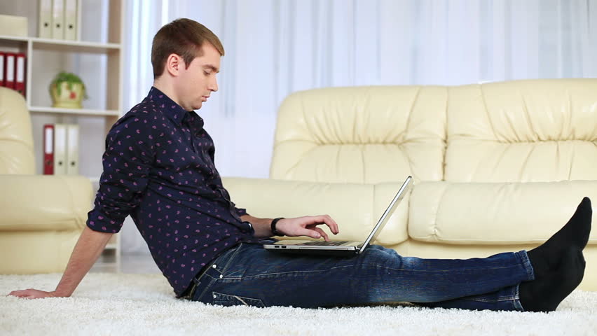Guy sitting on carpet with laptop. DOLLY HD 