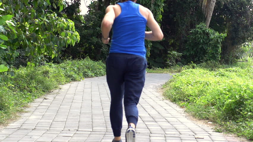 Young man jogging on path in park, super slow motion 240fps
