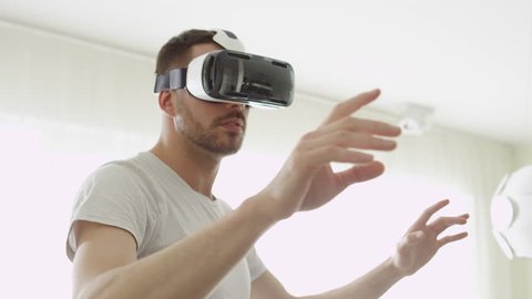 Man Wearing VR Headset at Living Room. Using Gestures with Hands. Shot on RED Cinema Camera.