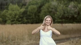 Beauty happy young girl with thumb up. Blond woman giving thumbs up for success. Portrait of happy caucasian person dressed in white summer casual clothing. Sign of success. Slow motion video footage.