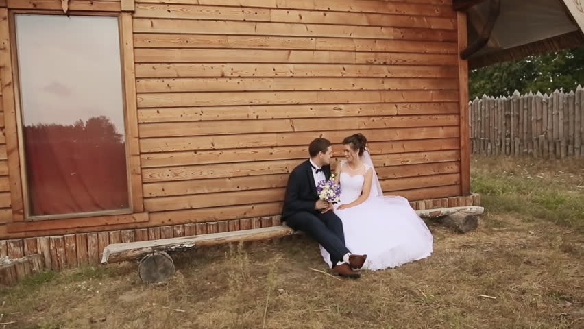 Bride and groom sit on a bench in the old house