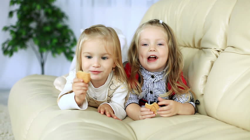Little sisters lying on the couch eating cookies. DOLLY HD 