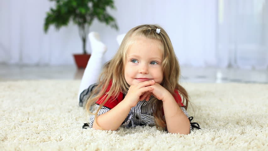 Little girl lying on the carpet looking to the camera. DOLLY HD 