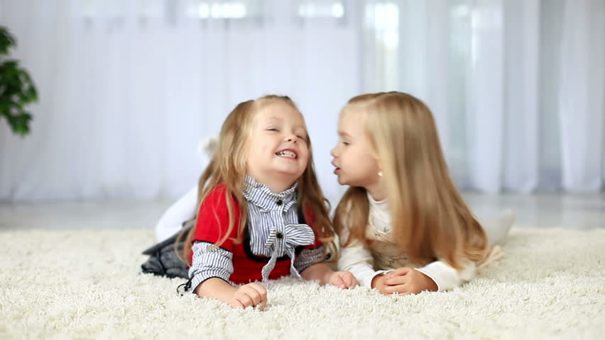 Sisters smiling while lying on the carpet. DOLLY HD 
