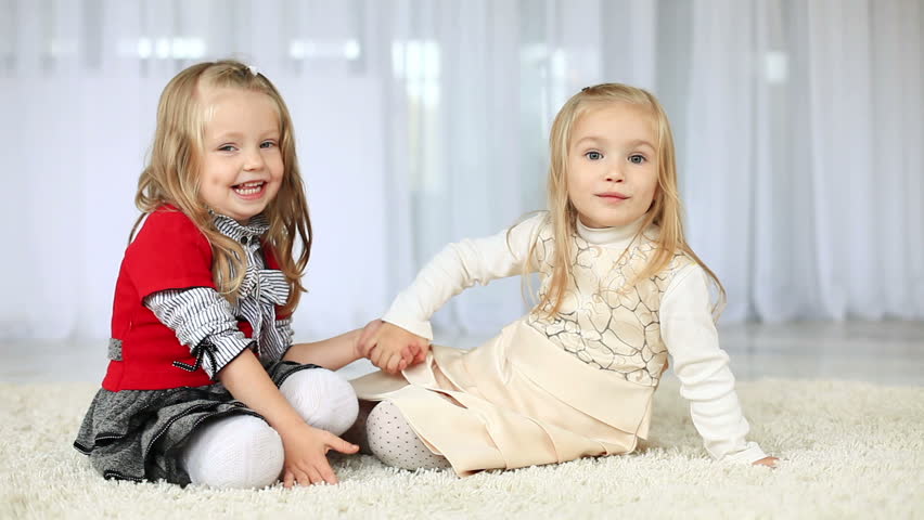Two happy  sisters looking at camera holding hands. DOLLY HD 